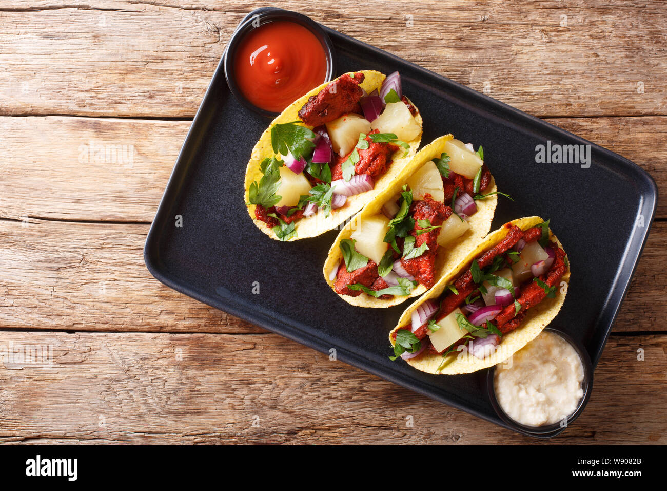 Mexican tacos al pastor served with sauce closeup on a plate on the table. horizontal top view from above Stock Photo