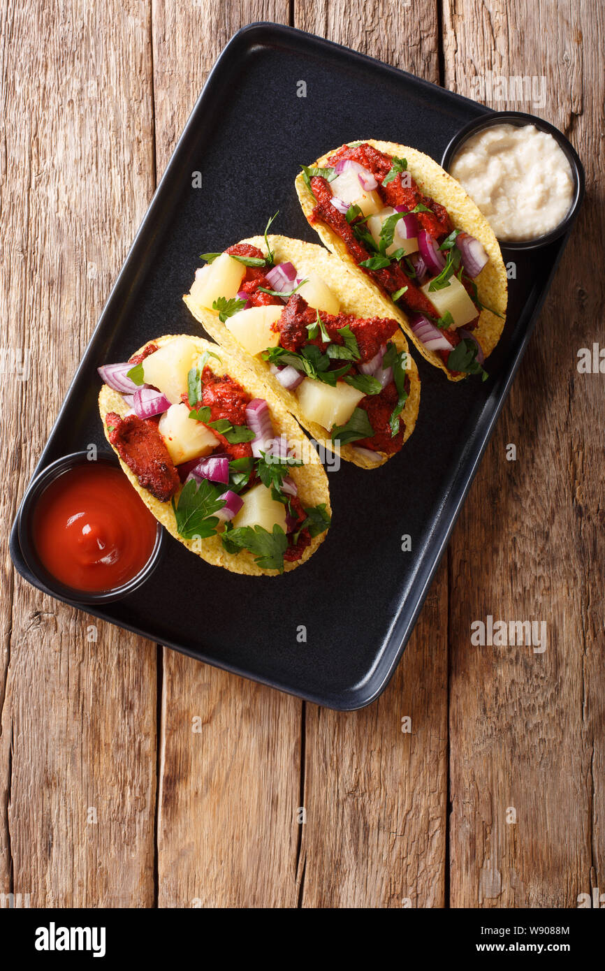 Mexican tacos al pastor served with sauce closeup on a plate on the table. Vertical top view from above Stock Photo