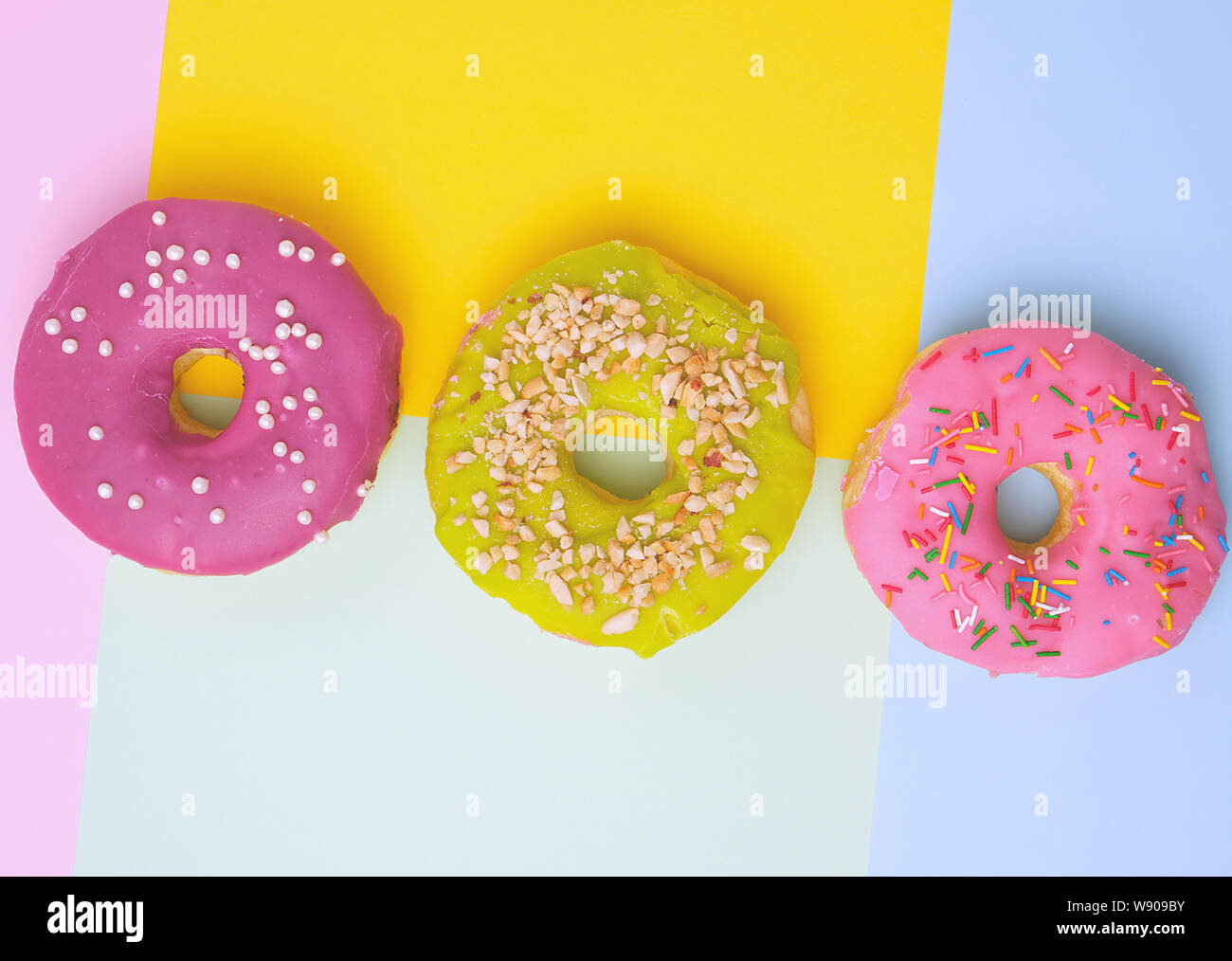 three round different sweet donuts with sprinkles on a colored ...