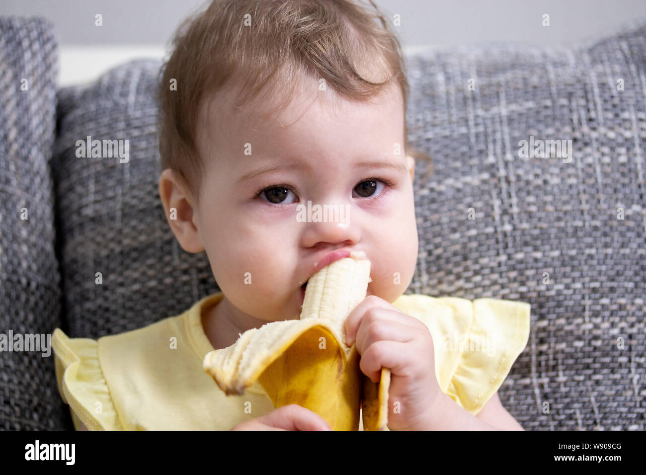 The child eats a banana. Portrait of a little baby girl close-up. Girl ...