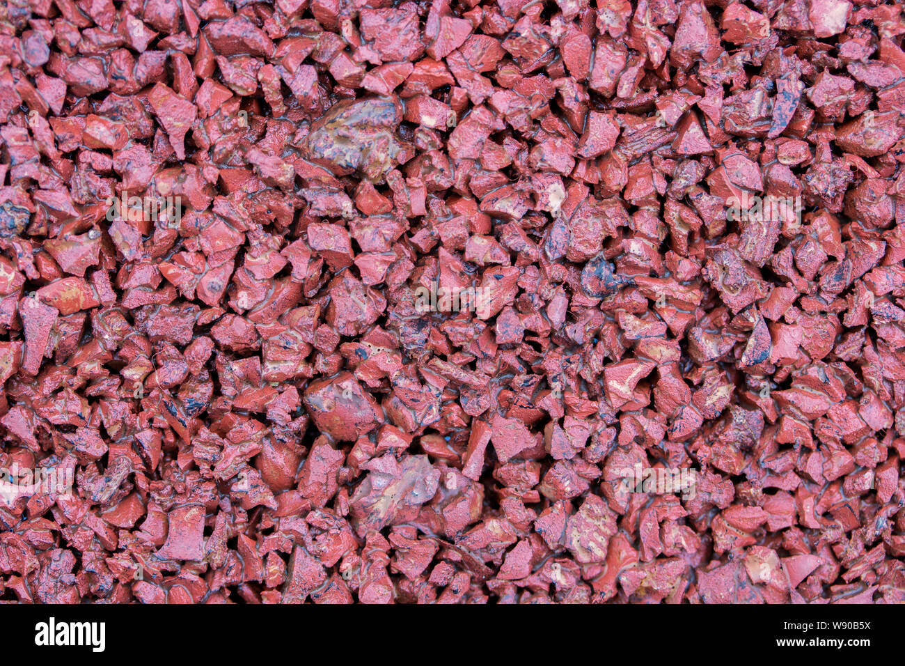 Red rubber covering of a sports ground for children. Texture granule