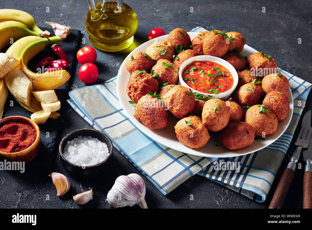 deep fried Plantain fritters Klako on a white plate with hot sauce