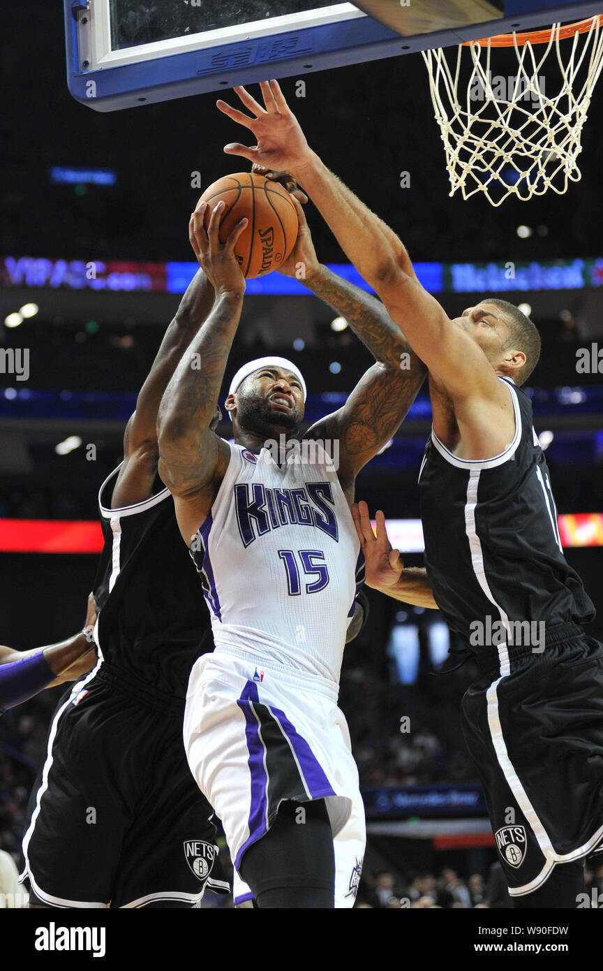 DeMarcus Cousins of Sacramento Kings, center, challenges Brook Lopez, right, and another player of Brooklyn Nets during an NBA exhibition game in Shan Stock Photo
