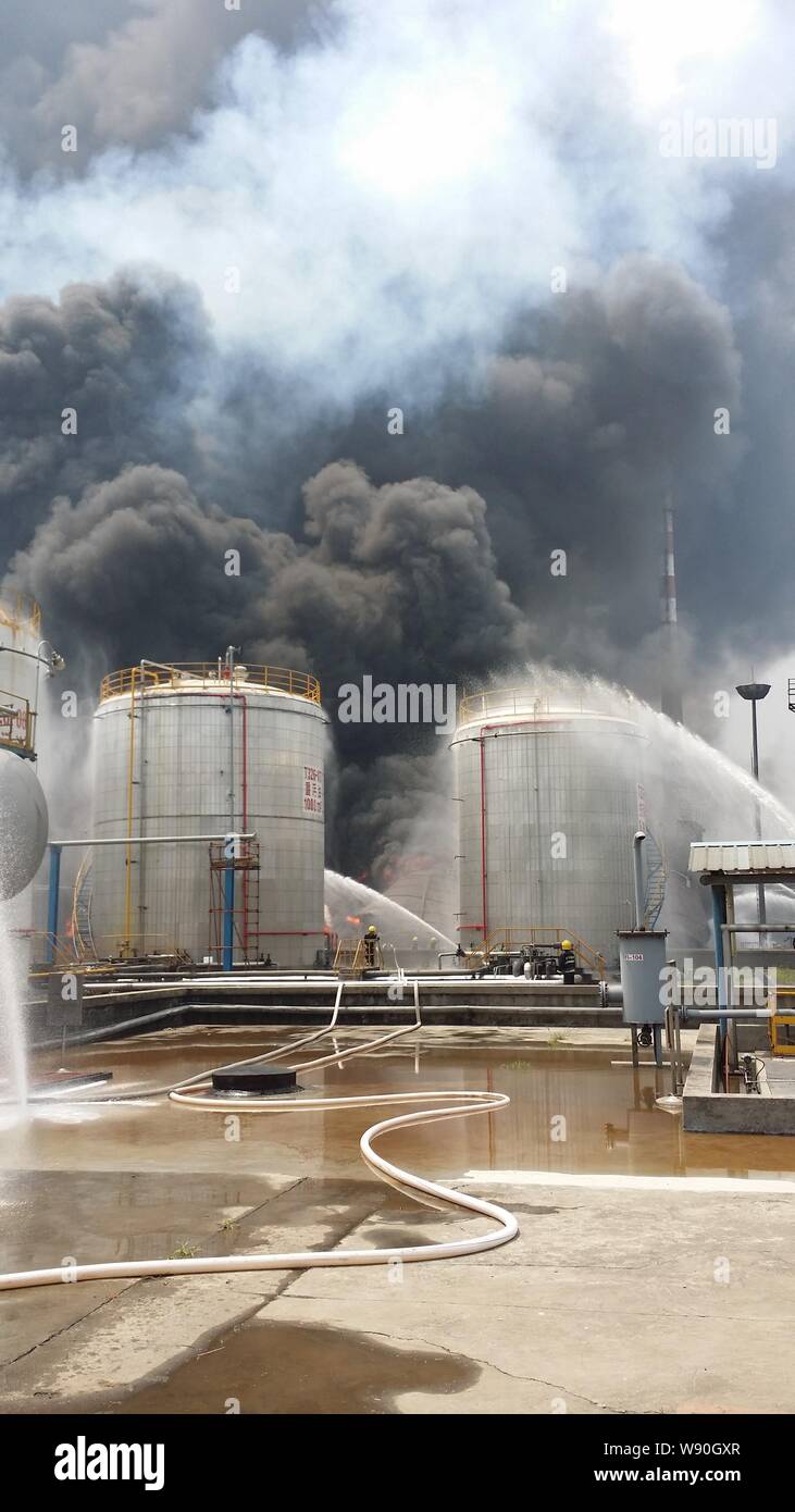 Chinese firefighters hose water to extinguish the fire after an explosion at an oil refinery of Sinopec Yangzi Petrochemical Company in Nanjing city, Stock Photo