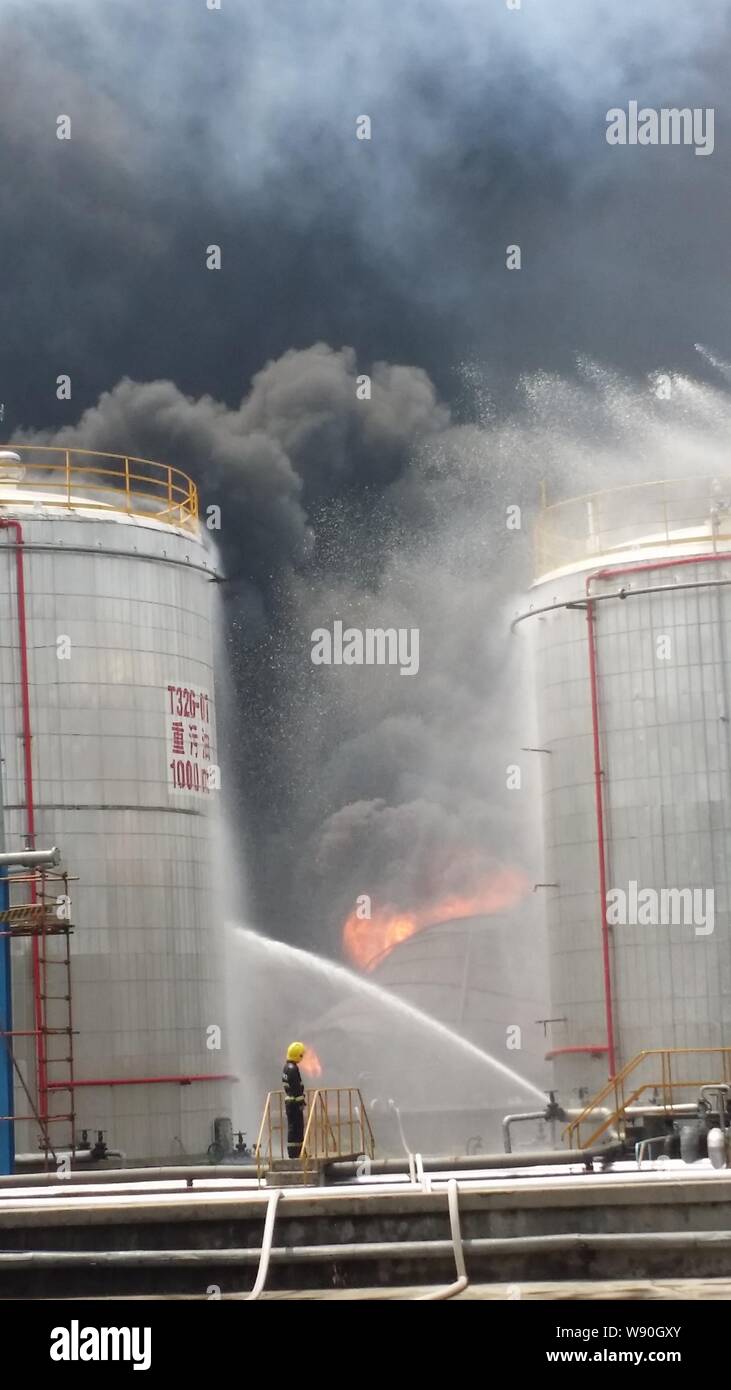 Chinese firefighters hose water to extinguish the fire after an explosion at an oil refinery of Sinopec Yangzi Petrochemical Company in Nanjing city, Stock Photo