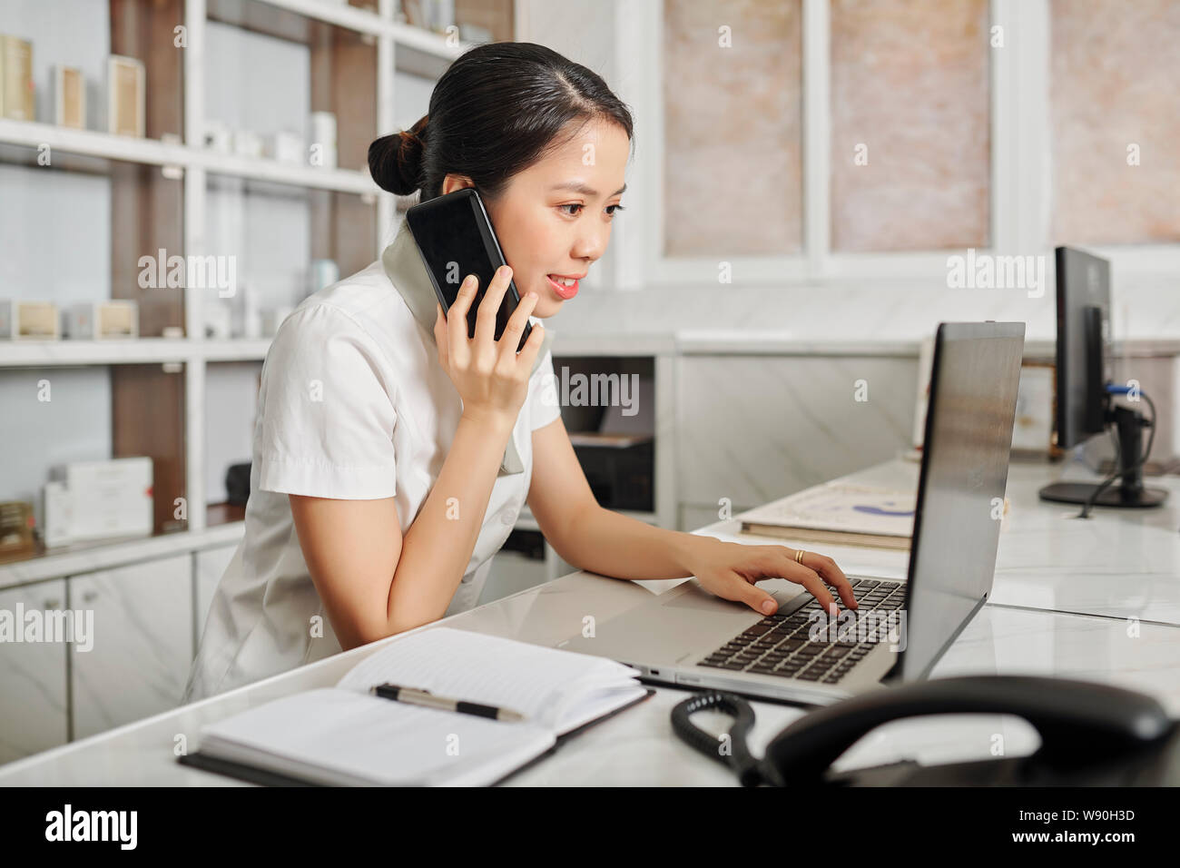 Receptionist Checking Schedule And Answering Phone Call Stock Photo Alamy