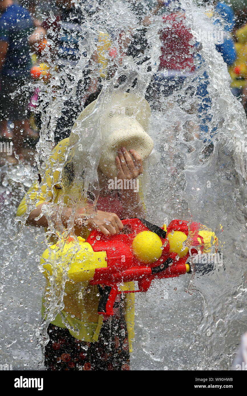 A young boy is splashed with water on the water-splashing square in Jinghong city, Xishuangbanna Dai Autonomous Prefecture, southwest Chinas Yunnan pr Stock Photo