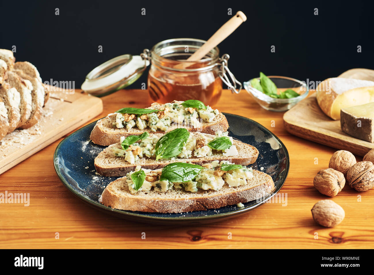 Full shot and focus stacking on a plate of toasts with roquefort cheese, walnuts, honey and basil Stock Photo