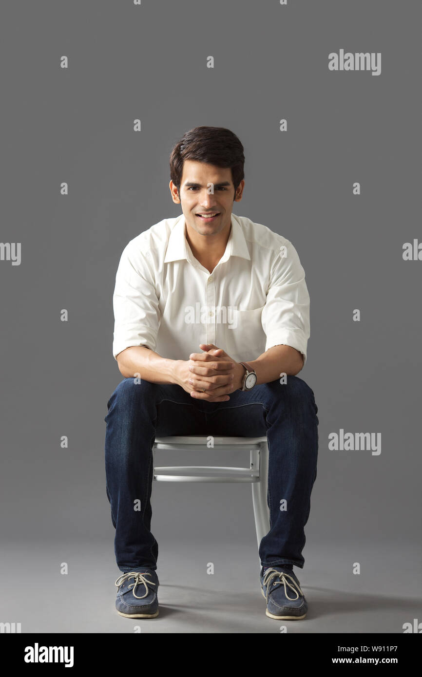 Young man sitting in a chair Stock Photo - Alamy