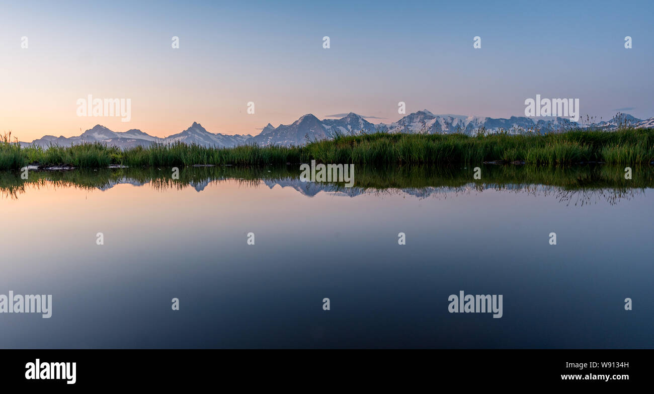Eiger, Mönch und Jungfrau spiegeln sich in kleinem Tümpel im Morgenrot Stock Photo