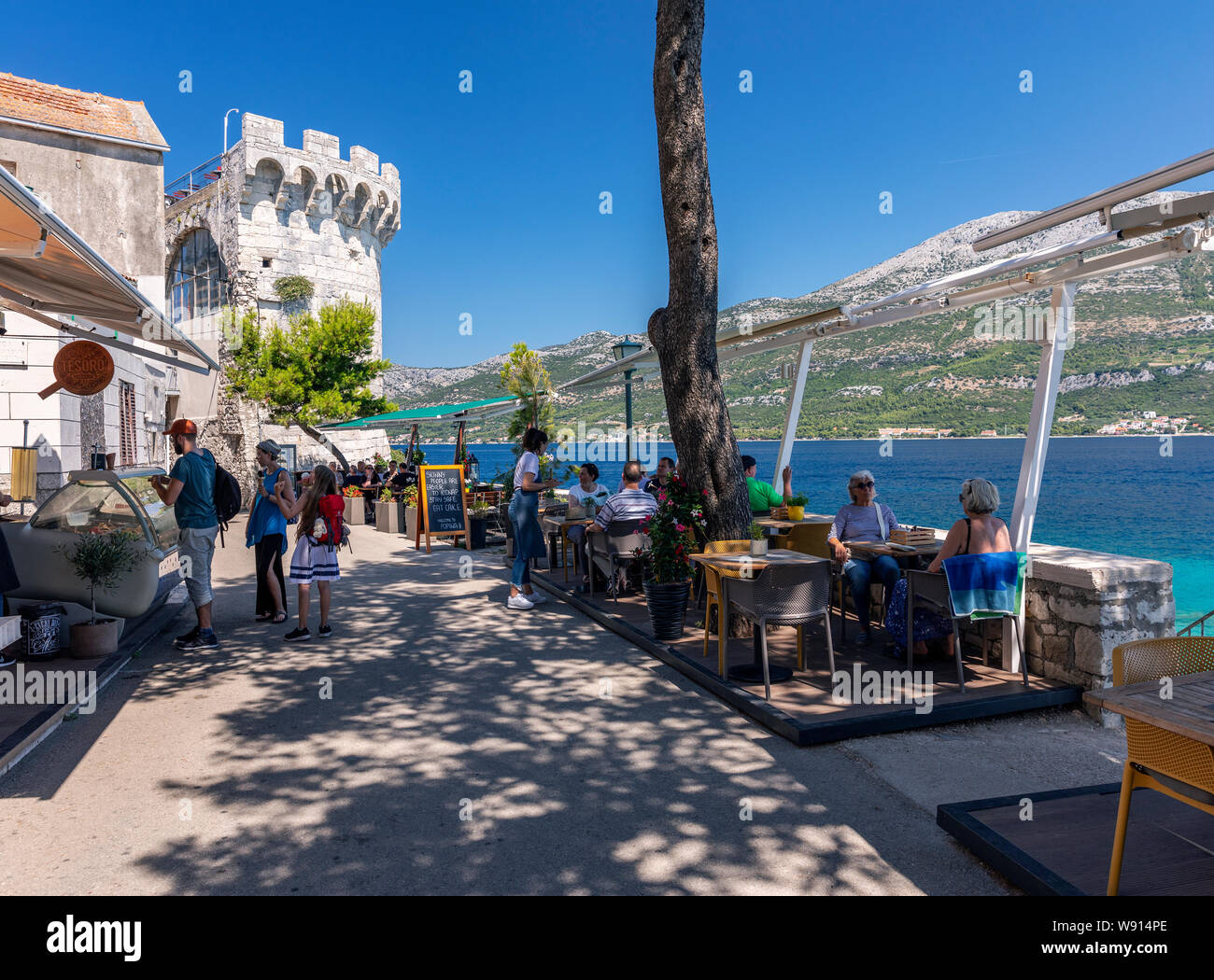 Tourists enjoying in a restaurant near Zakerjan tower in Korcula old town Stock Photo