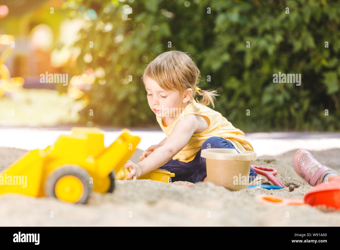 Little girl having lots of fun with her toys playing in the sandbox Stock Photo