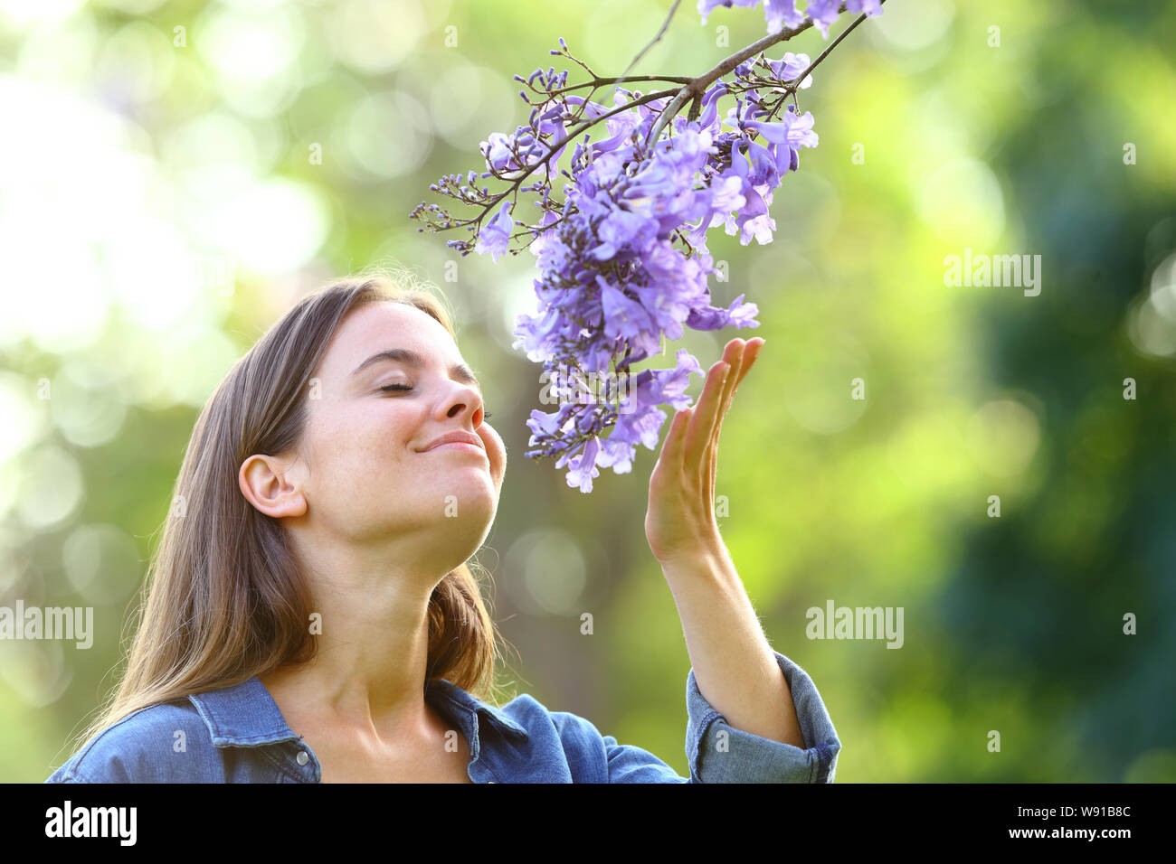 Candid woman smelling flowers standing in a park Stock Photo