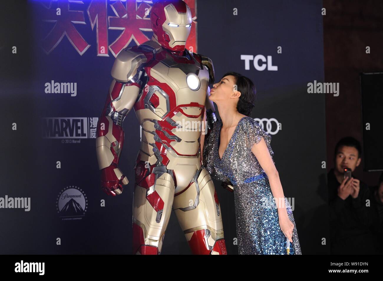 --FILE--A Chinese actress kisses a sculpture of Iron Man during the premiere of movie Iron Man 3 in Beijing, China, 6 April 2013.    When superhero fi Stock Photo