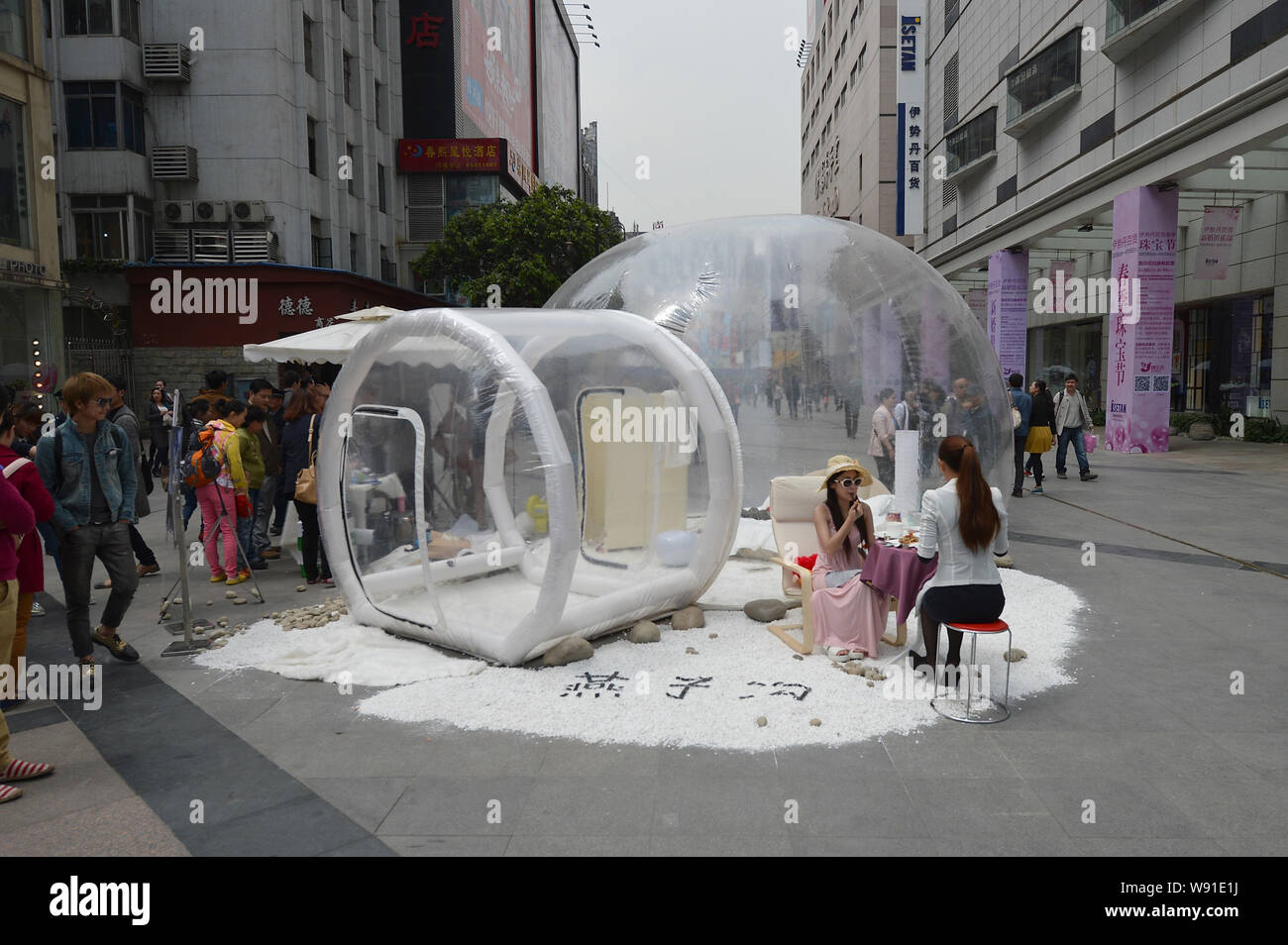 Chinese Models Chat Besides A See Through Bubble Room During