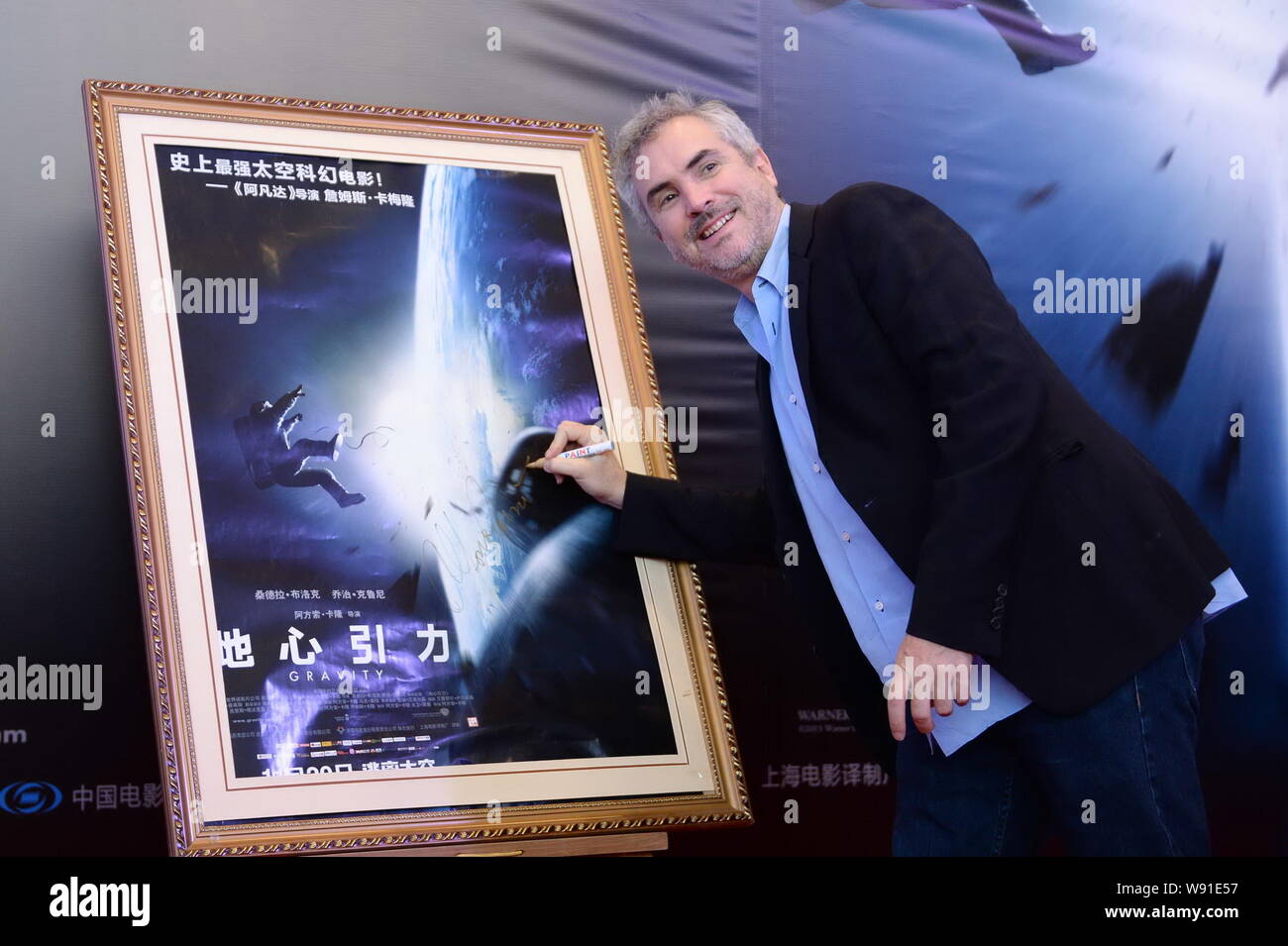Mexican film director Alfonso Cuaron autographs on a poster of his new ...
