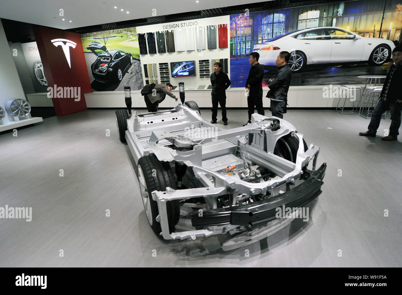 Visitors look at a chassis of the Model S on display at the Tesla store in Beijing, China, 5 November 2013.   US electric carmaker Tesla Motors opened Stock Photo