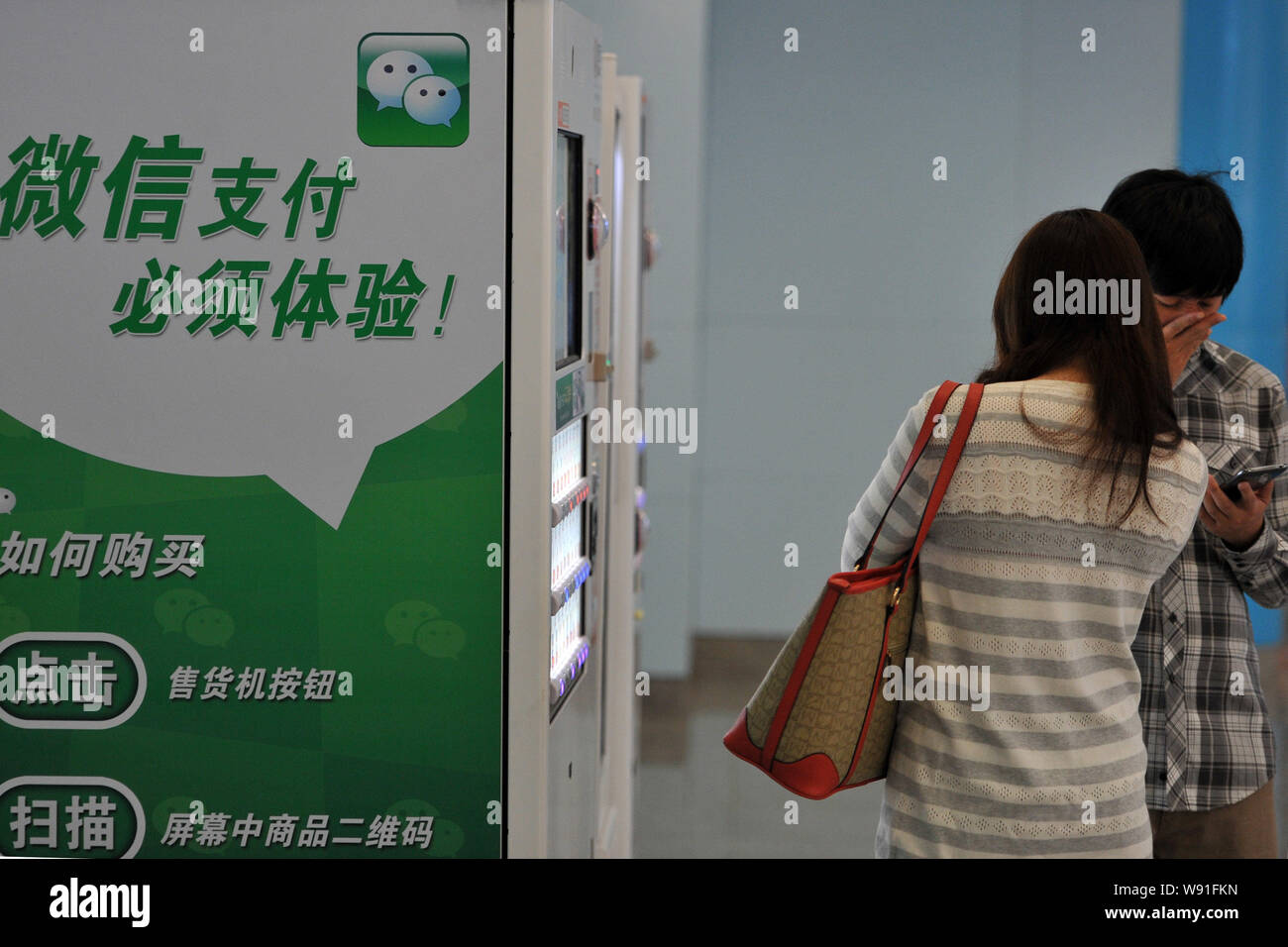 Chinese customers buy bottled drinks on a vending machine within the Wechat app in a subway station in Beijing, China, 26 September 2013.   WeChat use Stock Photo