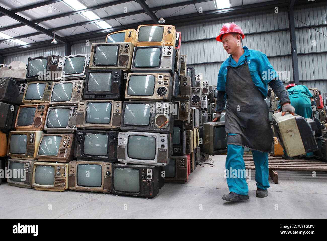 FILEA Chinese worker carries discarded outdated CRT (Cathode Ray Tube) TV sets to be