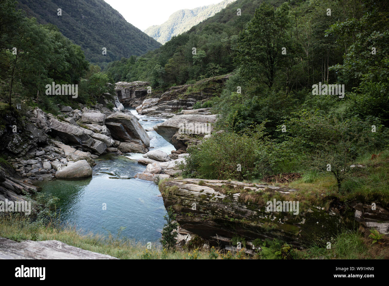 The Verzasca River flows over rocks and stones in the Verzasca Valley in Lavertezzo, in the Italian region of Ticino, Switzerland. Stock Photo