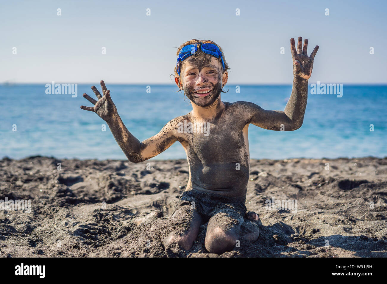 boys swiming at the black sea Black Friday concept. Smiling boy with dirty Black face sitting and playing  on black sand sea beach before swimming in ocean. Family active lifestyle  Stock Photo - Alamy