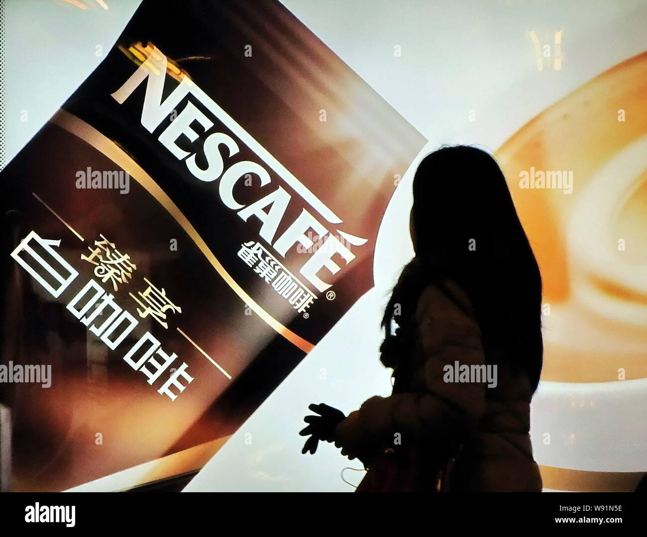 --FILE--A pedestrian walks past an advertisement for Nescafe coffee of Nestle in Shanghai, China, 11 January 2013.   Nestle announced plans to invest Stock Photo