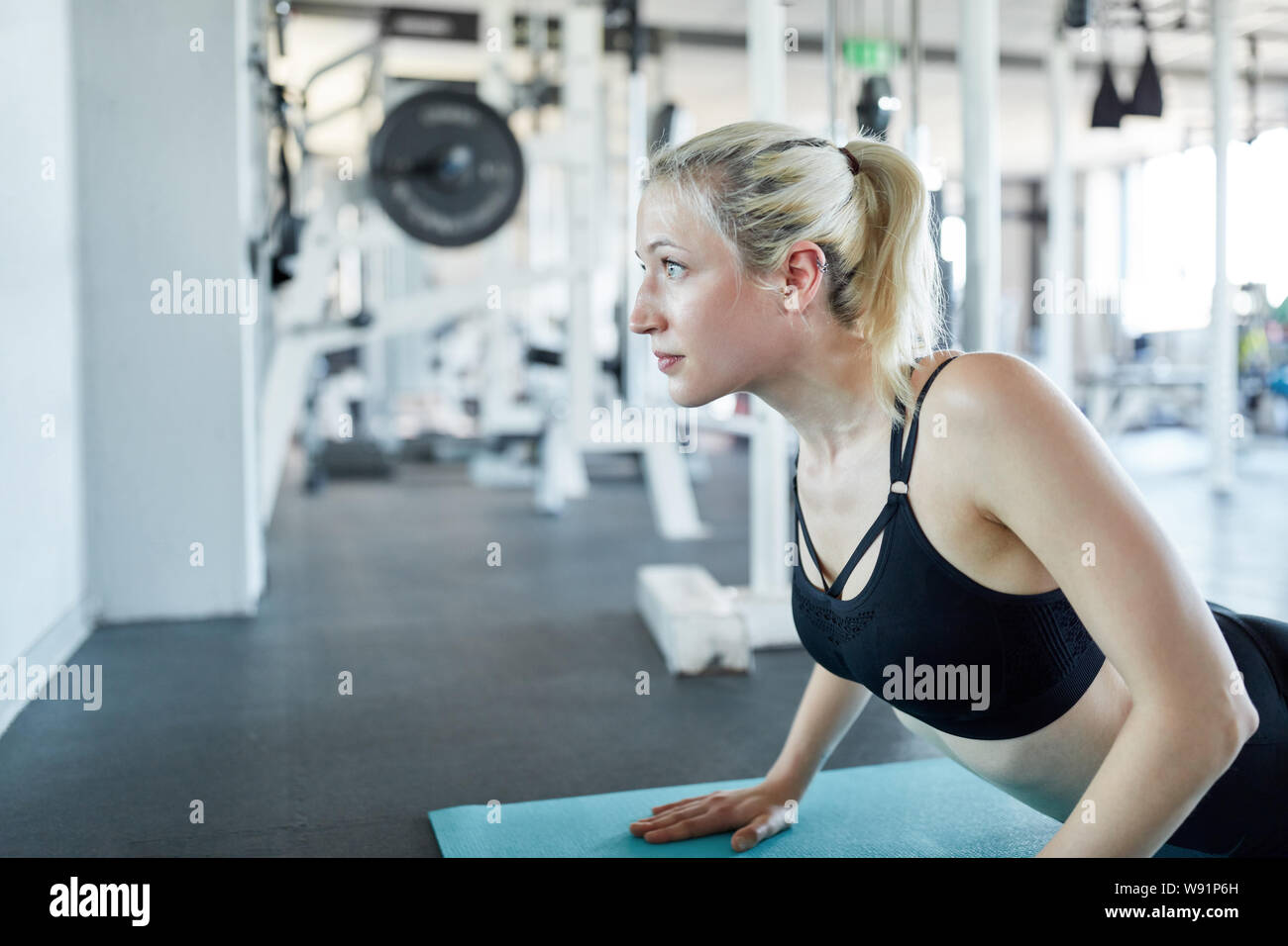 Young woman is doing a Pilates or yoga exercise on the mat in the gym class Stock Photo