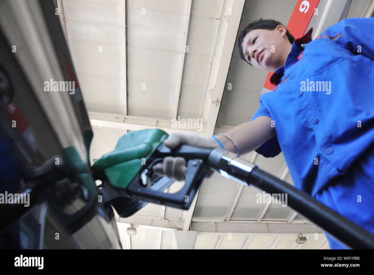 An employee refuels a car at a gas station of Sinopec in Linan, east Chinas Zhejiang province, 19 July 2013.    Sinopec Group, Asias largest refiner, Stock Photo