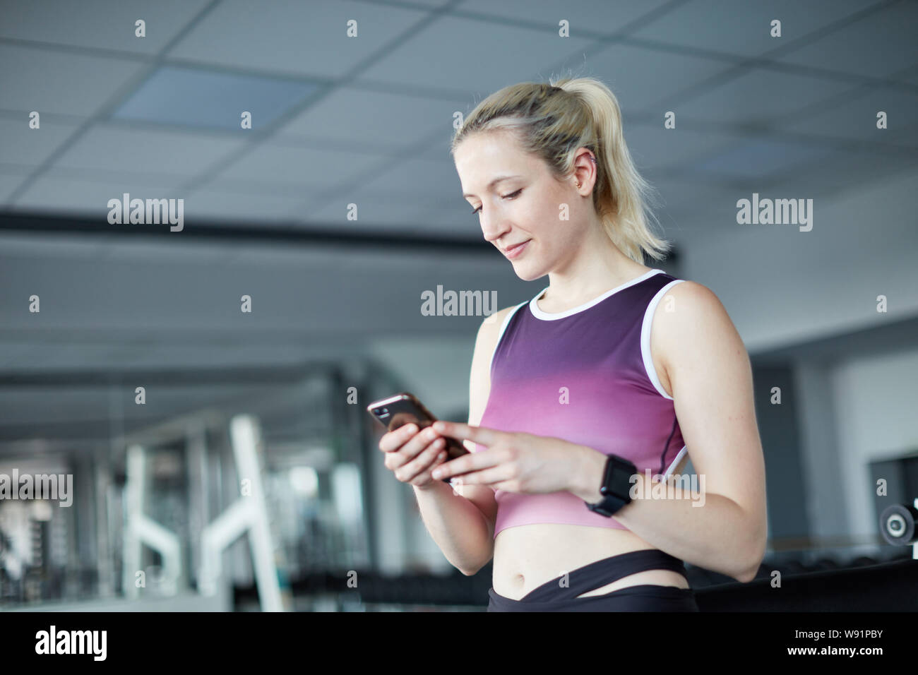 Sporty young woman uses her fitness app on the smartphone while exercising Stock Photo