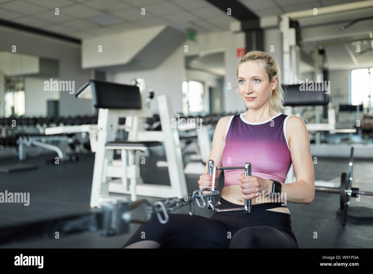 Woman rowing on cable with tight grip as strength training for the back Stock Photo
