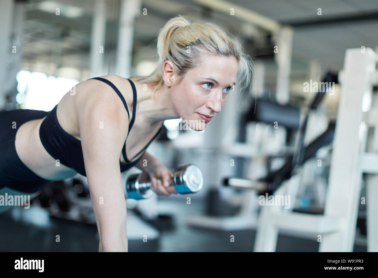 Young woman makes strenuous strength training for the triceps with a dumbbell Stock Photo