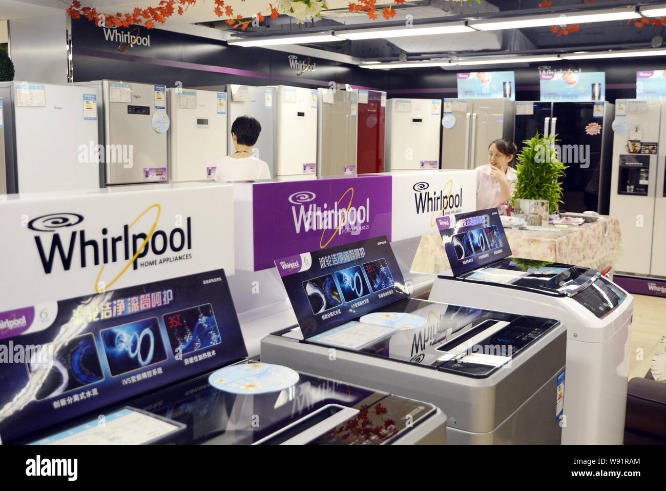 --FILE--A customer walks past Whirlpool washing machines as she shops for a Whirlpool refrigerator at a home appliances store in Dalian city, northeas Stock Photo