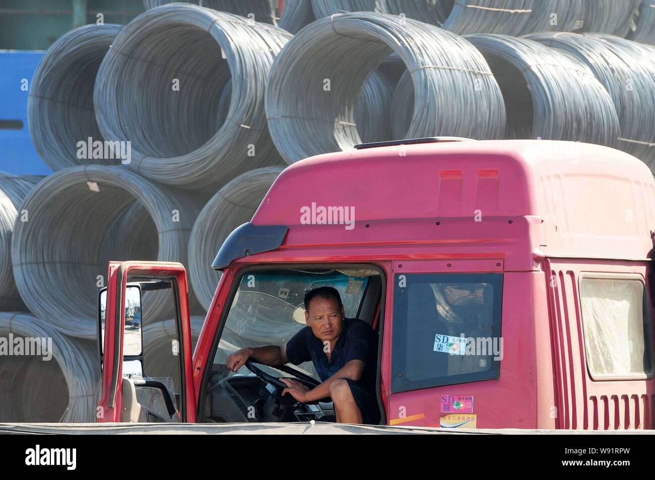 --FILE--A Chinese worker rests in his truck in front of a pile of coiled steel bars on a quay in Qingdao city, east Chinas Shandong province, 21 Augus Stock Photo