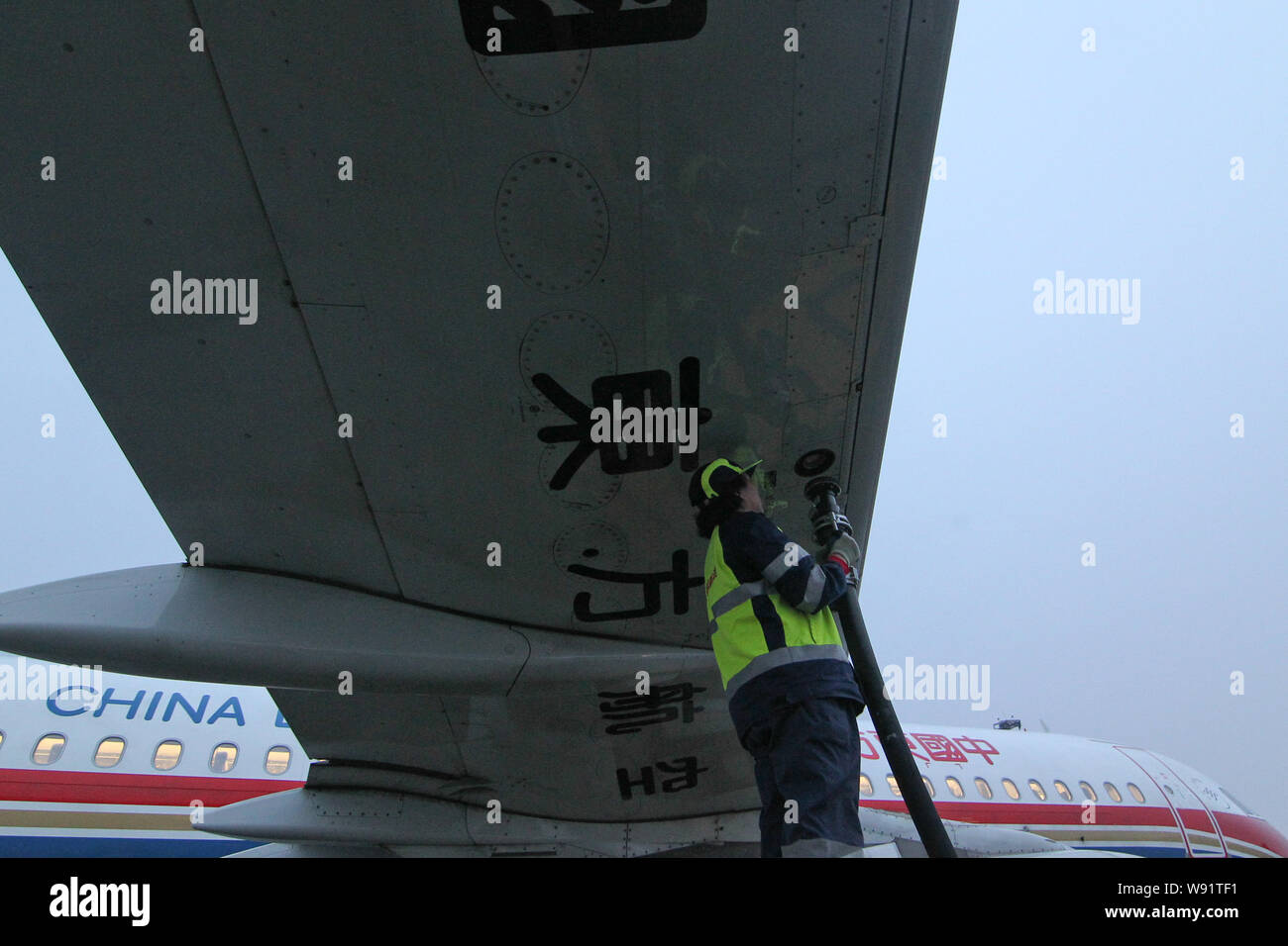 A Chinese ground crew member fuels an Airbus A320 jet plane of China Eastern Airlines with
