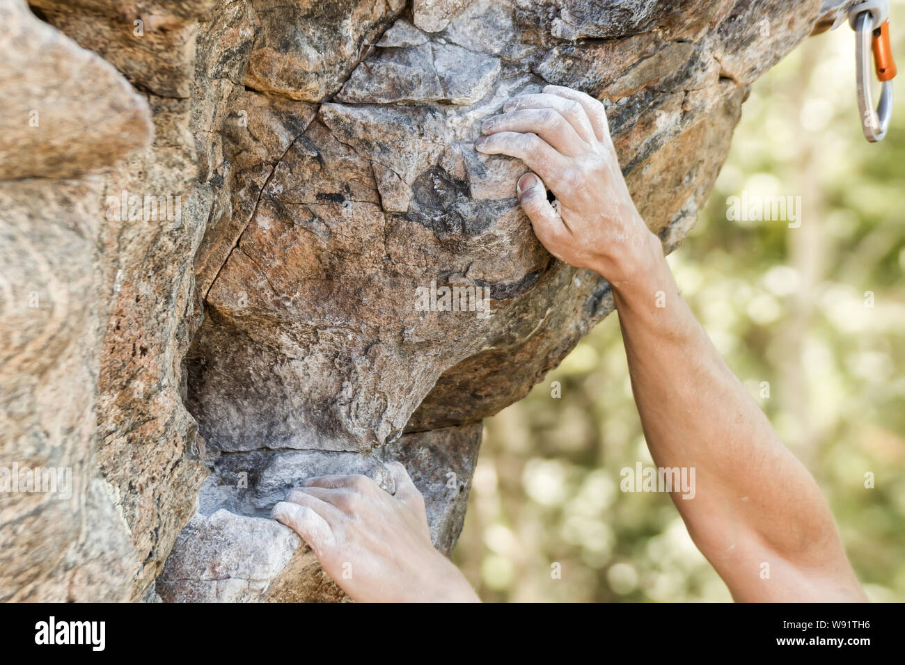 Closeup view of rock climber's hand gripping hold on natural cliff