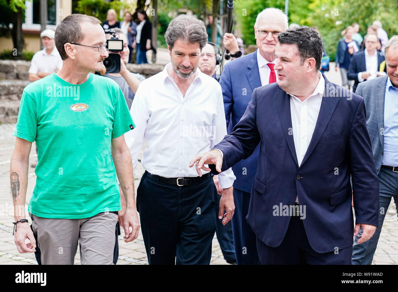Heidelberg, Germany. 12th Aug, 2019. Hubertus Heil (r-l, SPD), Federal Minister of Labour and Social Affairs, talks to Stephan Götte, Managing Director of the Heidelberg Waldorf School Association, and former long-term unemployed Markus Schmitt at the Freie Walddorfschule. The Secretary of Labor is on a summer trip. Credit: Uwe Anspach/dpa/Alamy Live News Stock Photo