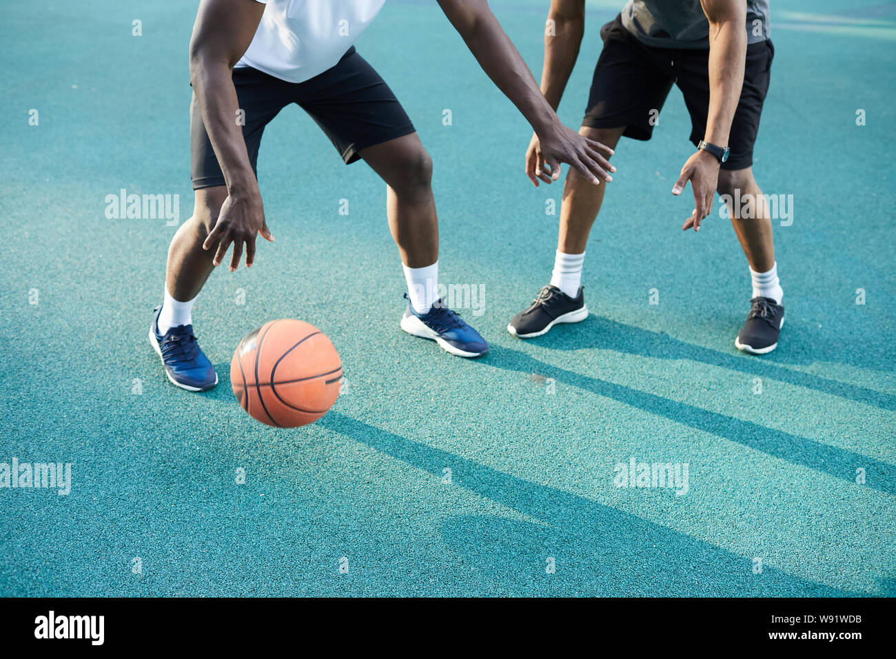 Low angle action shot of two AfricanAmerican guys playing basketball