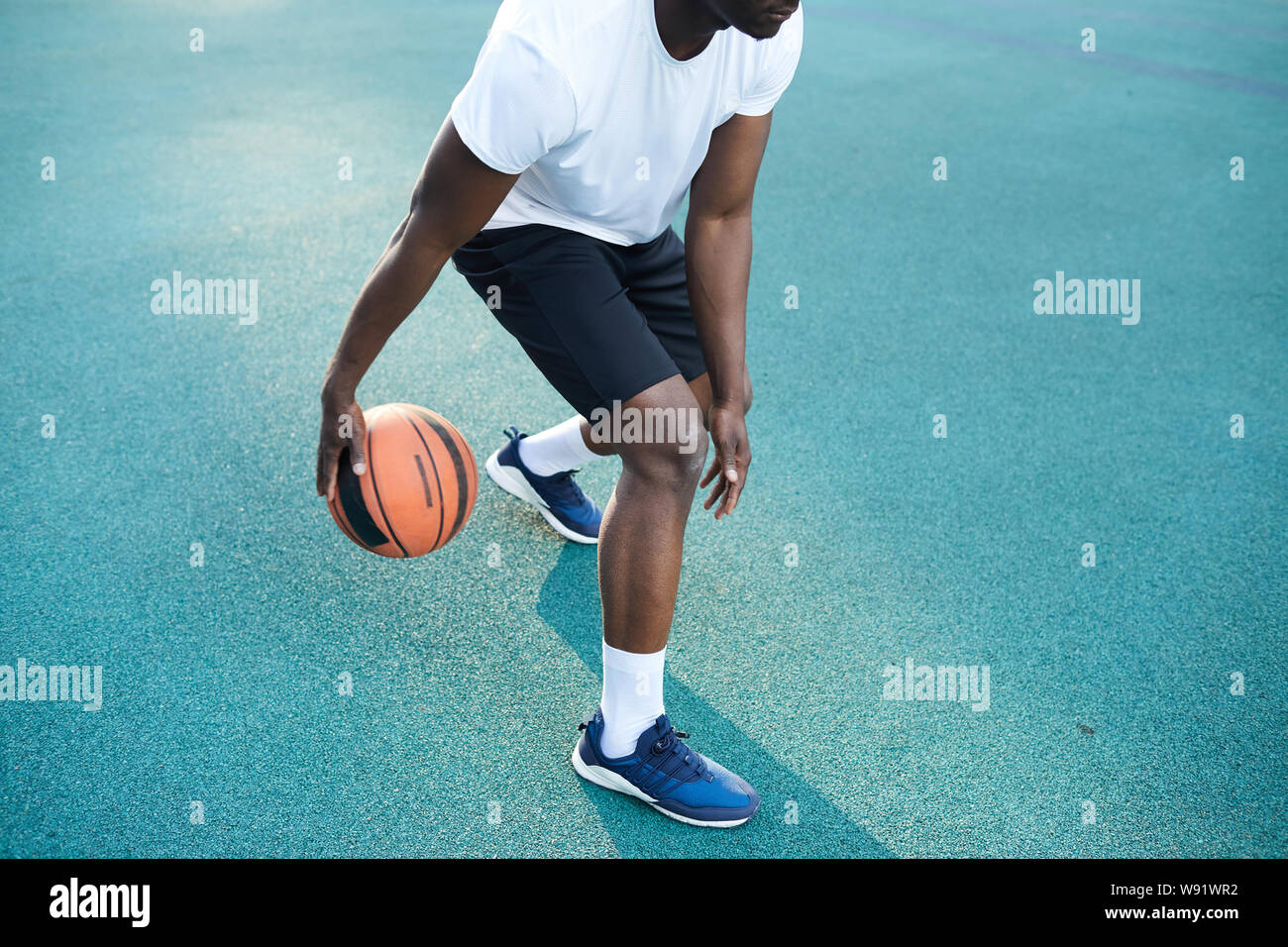 Action shot of unrecognizable African man playing basketball outdoors, copy space Stock Photo
