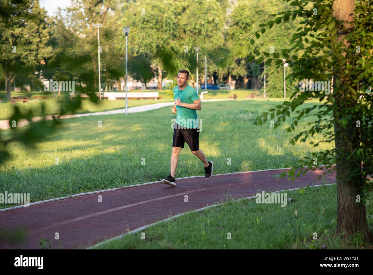 Handsome young sportsman jogging in nature Stock Photo