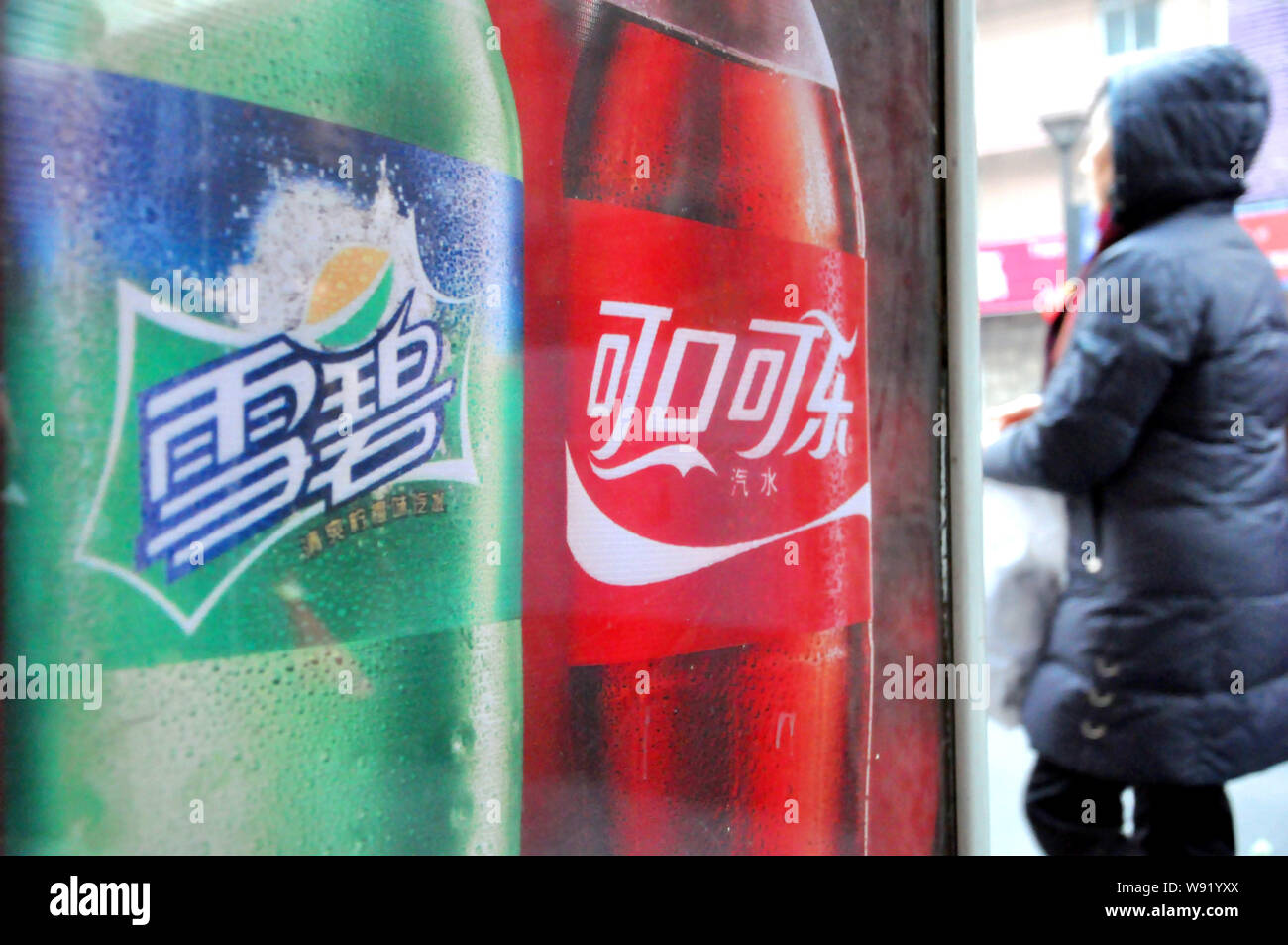 FILEA pedestrian walks past an advertisement for Cola and Sprite