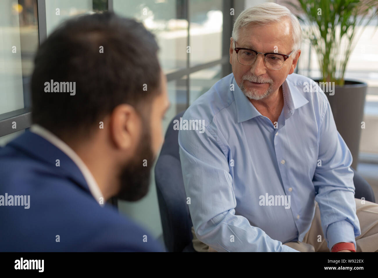 Handsome Grey Haired Man Looking At His Colleague Stock Photo
