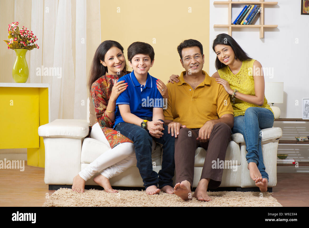 Family sitting on a couch and smiling Stock Photo - Alamy