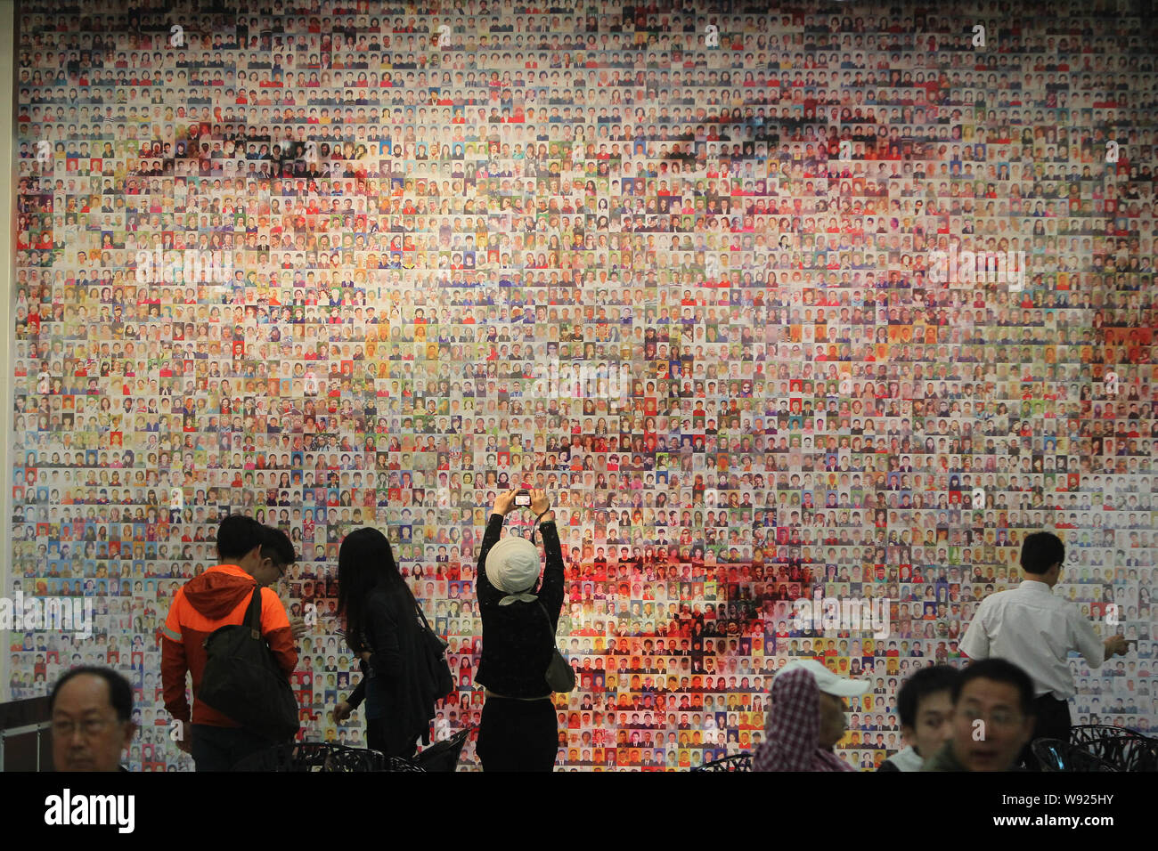 Visitors look at or take pictures of a wall of a smiling face consisting of thousands of photos at the Shanghai Film Museum in Shanghai, China, 13 Jun Stock Photo