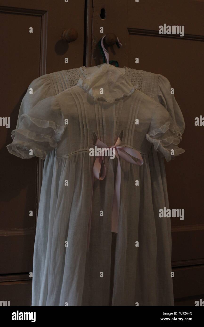 Vintage ribbonwaisted Edwardian Dress suspended from a dresser on set period costume."Dressed