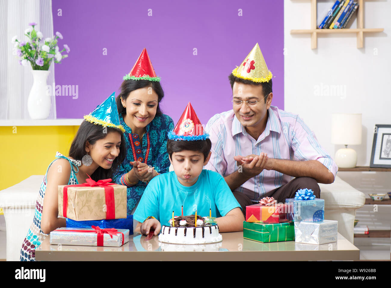 Boy blowing out birthday candles with his family Stock Photo