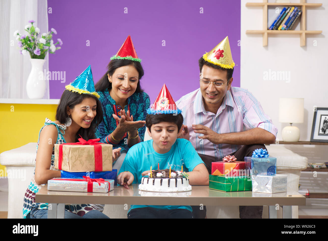 Boy blowing out birthday candles with his family Stock Photo