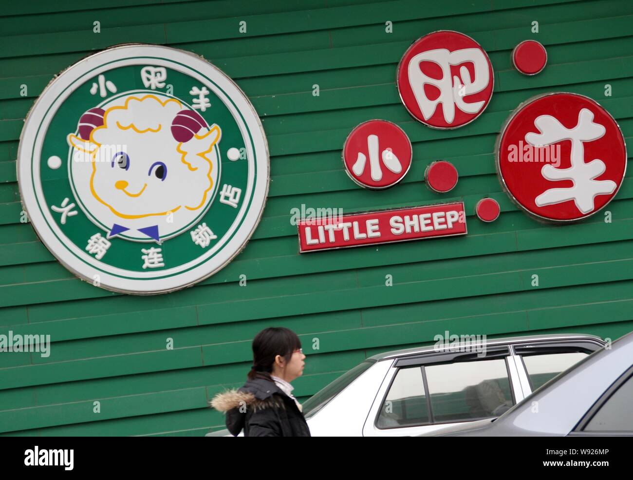 --FILE--A pedestrian walks past a logo of Yum brand Little Sheep in Beijing, China, 16 January 2012.   Yum! Brands Inc, owner of KFC, Pizza Hut, and T Stock Photo