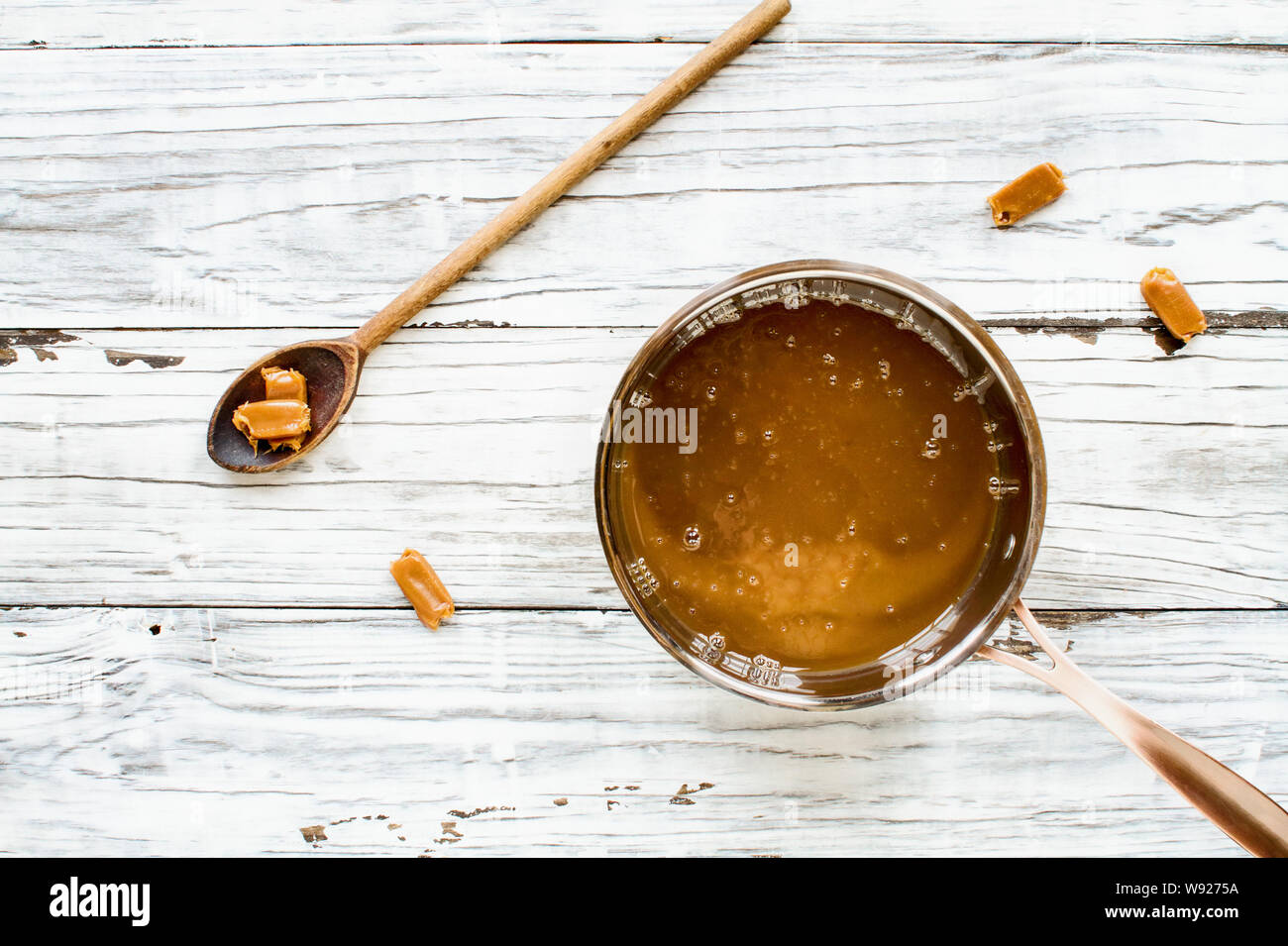 Sauce pan of melted caramel sauce with wooden spoon and candy pieces