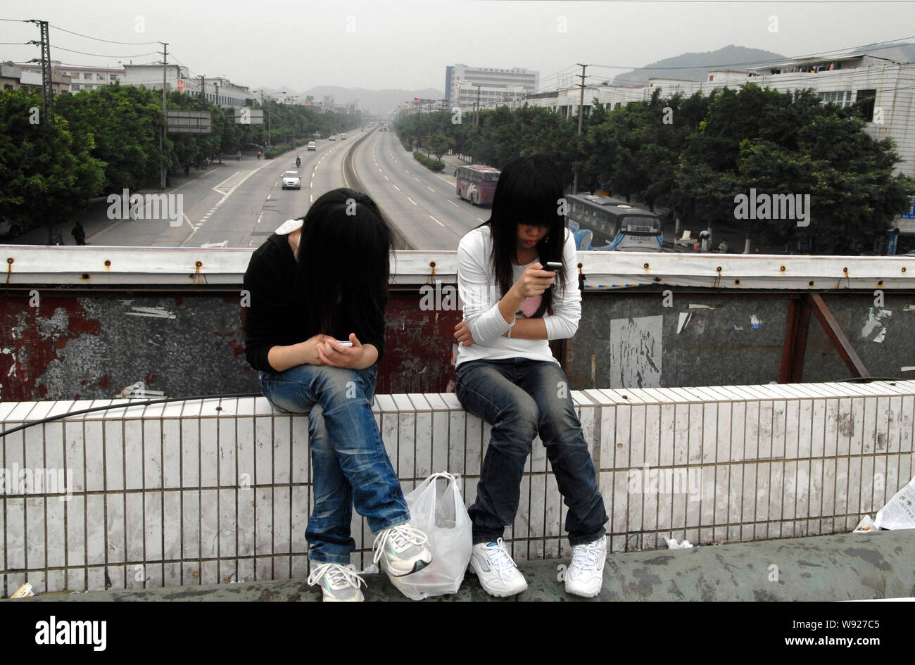 FILE--Two young female Chinese migrant workers use their mobile phones on a  footbridge in an industrial park in ChangAn town, Dongguan city, south C  Stock Photo - Alamy