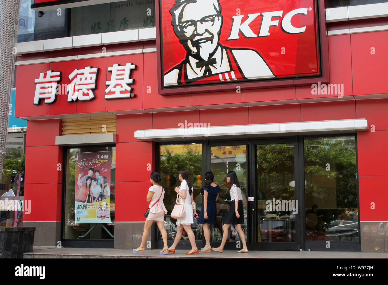 Pedestrians walk past a KFC fastfood restaurant in Haikou city, south Chinas Hainan province, 13 May 2013.   Sales of fast food giant KFC in China slu Stock Photo